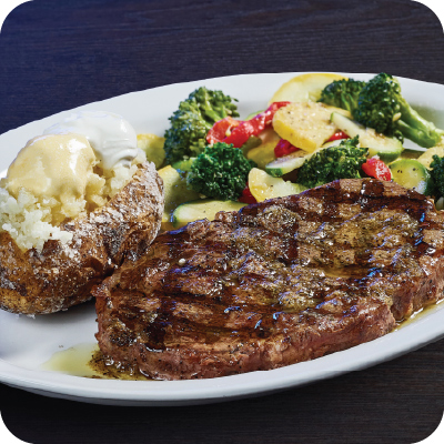 ribeye steak with a baked potato and veggies