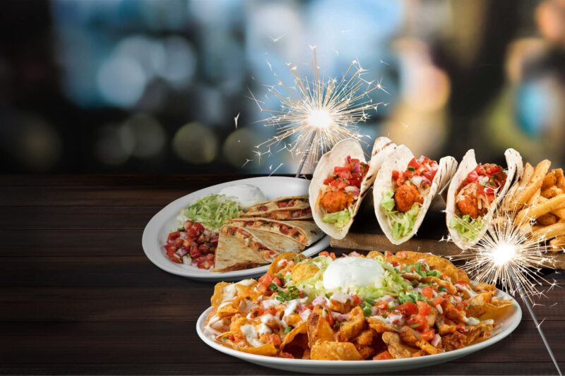 a plate of zinger nachos, zinger tacos and zinger quesadillas with fireworks