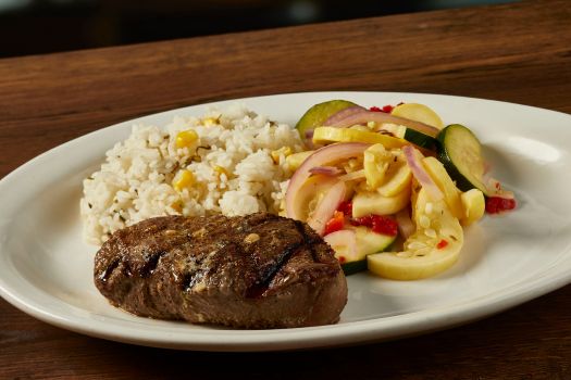 a plate of filet mignon with veggies and fries